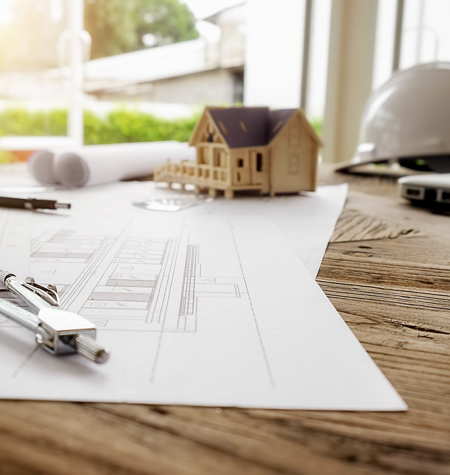 Plano de ingeniería con herramientas y modelo de casa